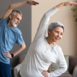 Elderly woman and man stretching arms together at home.