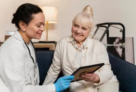 Nurse showing a tablet to an older woman in a clinic.