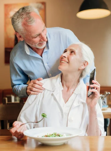 Elderly man comforting senior woman enjoying a meal.