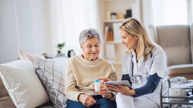 Nurse explaining medication to senior patient at home.