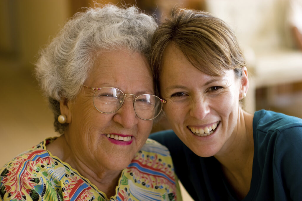 Young woman hugging cheerful older lady.