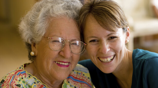 Young woman hugging cheerful older lady.