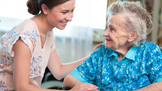 Young woman offering support to senior in a wheelchair