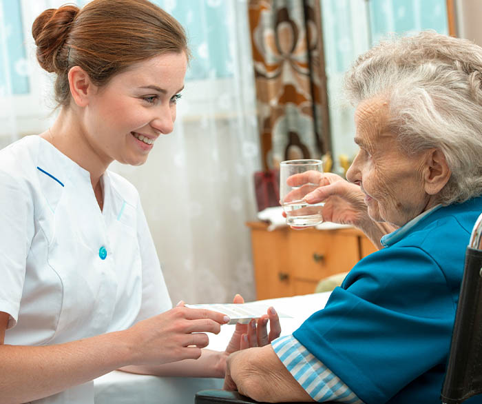 Nurse assisting an elderly patient with medication.
