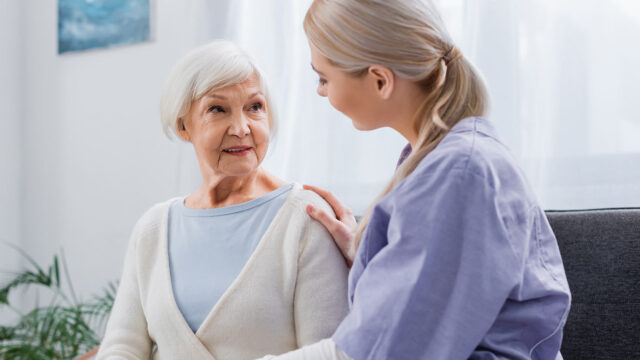 Healthcare worker assisting senior with shoulder check.