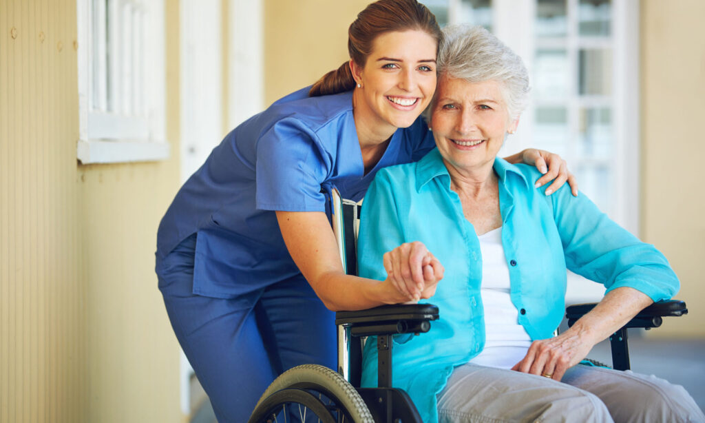 Caregiver supporting a senior woman in a wheelchair.