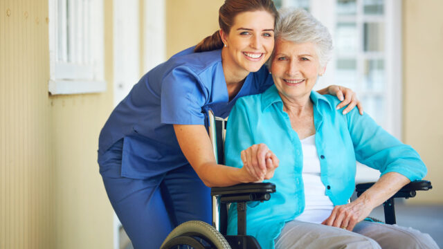 Caregiver supporting a senior woman in a wheelchair.