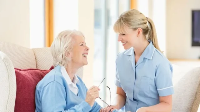 Staff member conversing closely with elderly woman.