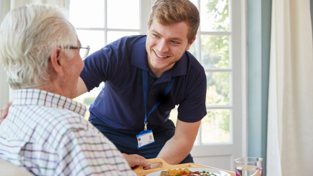 Care worker serving food to elderly people.