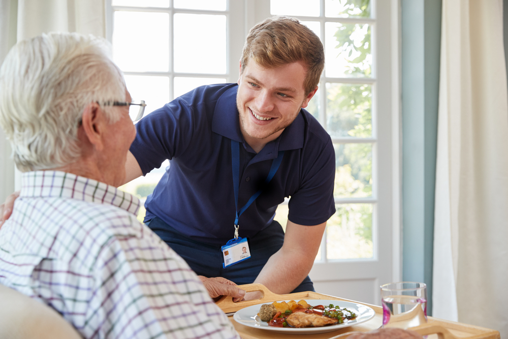 Care worker serving food to elderly people.