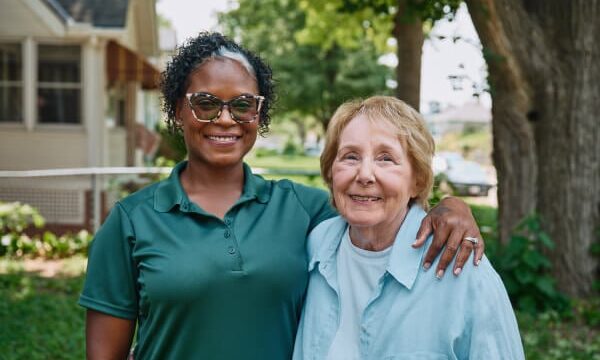 Caregiver standing with senior outdoors.