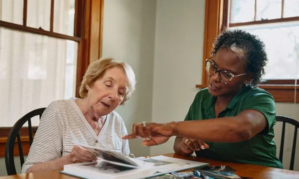 Caregiver showing a photo album to elderly woman.