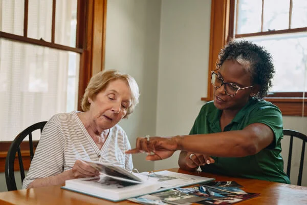 Caregiver showing a photo album to elderly woman.