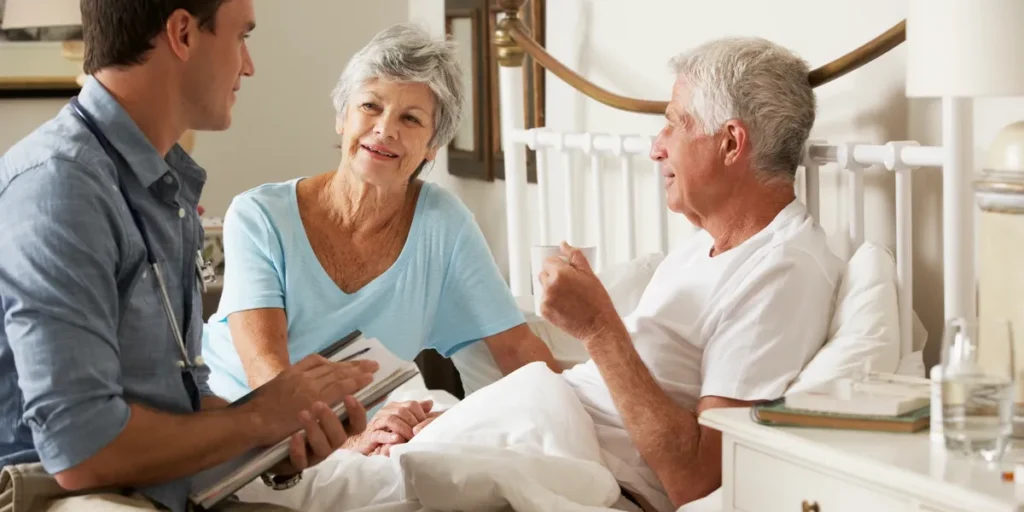 A caregiver and an elderly woman have a thoughtful conversation in a cozy room, both smiling.
