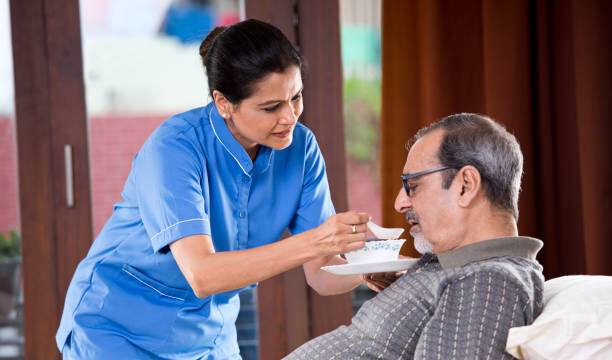 Healthcare worker feeding soup to an older man.