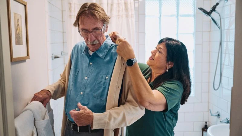 A healthcare professional assists an elderly man with a gentle touch, helping him with his daily tasks.